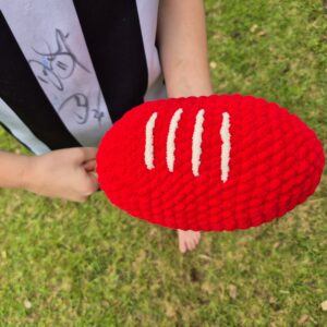 A kid ready to handball a red plush indoor football